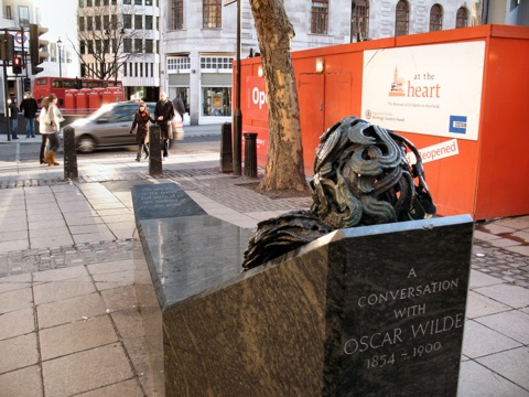 Oscar Wilde's head and hand rising out of a granite bench beside Adelaide Street