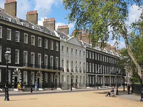 The west side of Bedford Square: a dark-brick Georgian terrace with white window frames and railings, the square's trees in front