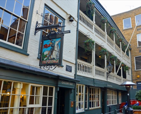 The George's white-painted front with its two tiers of wooden galleries hung with baskets of ivy, a painted inn sign of St George on horseback dated 1676, and green-framed windows of the Gallery Bar below.