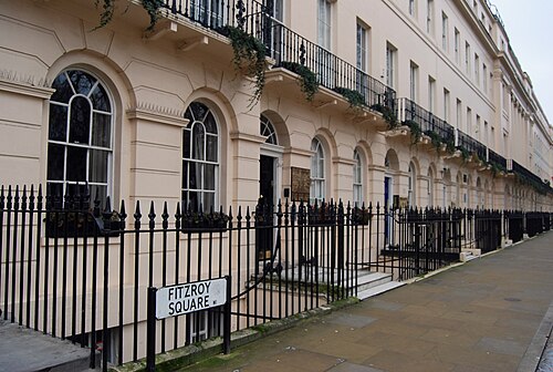 The white stucco of Fitzroy Square, with the street's nameplate on the railings and the garden's trees beyond