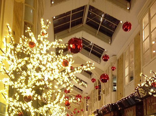 Burlington Arcade under its glass roof, hung with Christmas lights and red baubles above the shopfronts