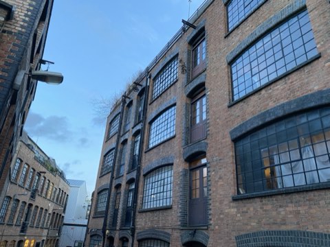 A brick warehouse with tall iron-framed windows against a clear sky