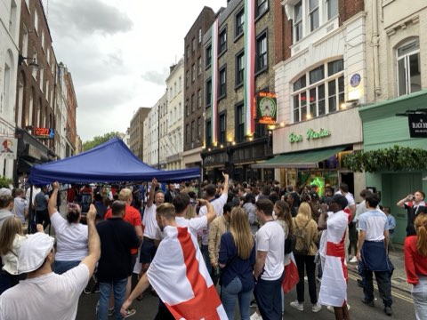 A Soho street filled with England supporters in flags and shirts during a European Championship match