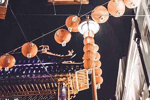 Red paper lanterns strung across a Chinatown street at dusk