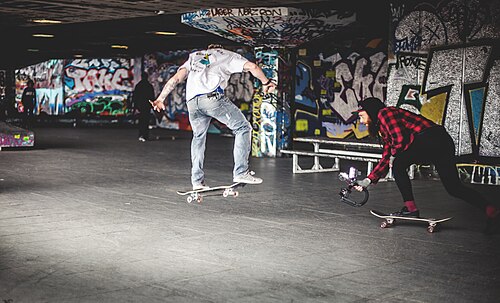 A skateboarder in the air in the Undercroft beneath the Southbank Centre, graffiti behind