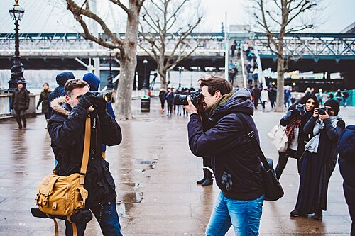 People walking along the Queen's Walk on the South Bank, with trees and the river beside them