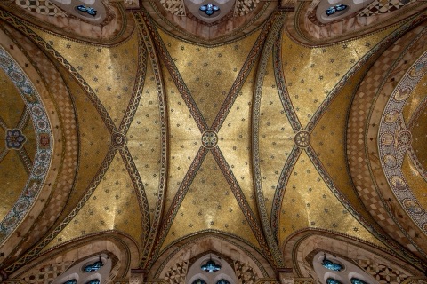 Straight up at the vault: gold mosaic panels scattered with small stars, crossed by patterned ribs meeting at a roundel, with the tops of arched windows at the edges.