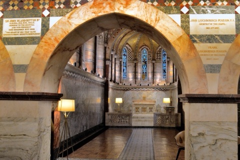 Through a marble arch to the altar at the far end of a lamp-lit passage of marble walls, with memorial tablets to the hospital's surgeon and to the two Pearsons set into the wall around the arch.
