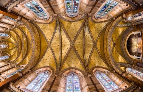 The ceiling of the chapel from below: gold mosaic vaults crossed by patterned ribs, marble-lined walls and stained-glass windows all round.