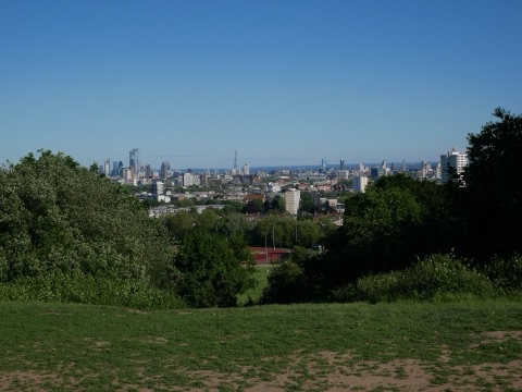 The view south from Parliament Hill over grass and trees to the City skyline