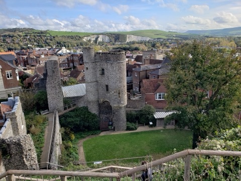 Lewes Castle's flint barbican and gatehouse among the red roofs of the town, with the white chalk of the Downs and green hills behind.