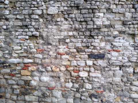 The face of the Roman wall at Tower Hill: rough grey ragstone blocks laid in rows, with courses of flat red tiles running through them
