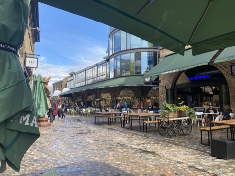 Camden Market's cobbled yard, trestle tables and parasols in front of the brick arches