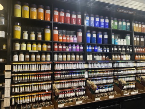 Shelves of pigment in glass jars above racks of oil colours and brushes at Cornelissen