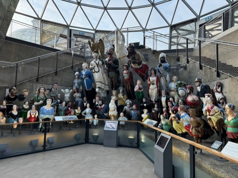 Rows of painted ship's figureheads on stands under the glass roof of the undercroft