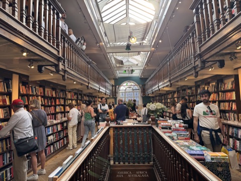 Daunt Books' long oak gallery under a barrel skylight, shelves either side and a table of books below