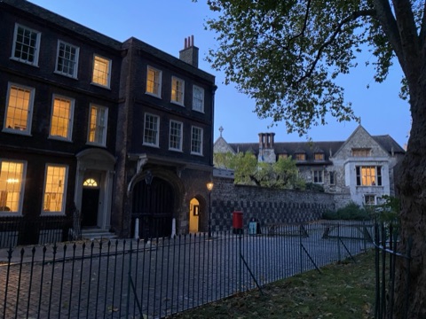 Charterhouse Square at dusk, lit windows in the Georgian range and the gatehouse beyond