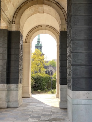 Bronze name panels either side of an arch in the memorial, a church tower beyond
