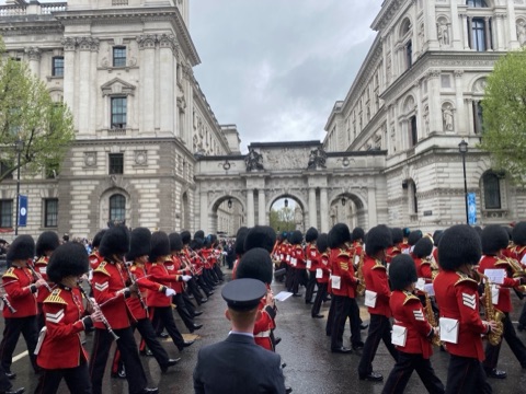 A guards band in bearskins and scarlet marching down Whitehall past the government buildings