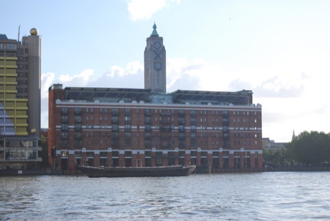 The Oxo Tower and its wharf building seen from across the Thames, the lettered tower rising above the brick front