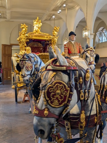The Gold State Coach in the Royal Mews, with model horses harnessed in red and gold