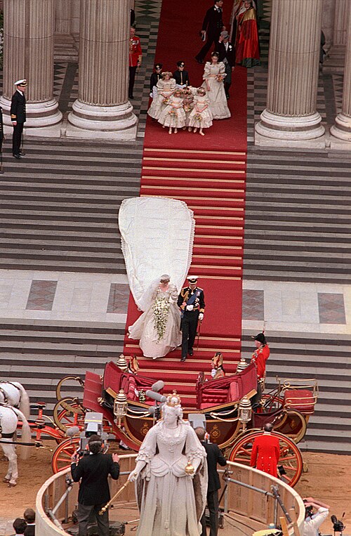 Charles and Diana coming down the steps of St Paul's after the wedding, her train spread out behind her, the open carriage waiting below