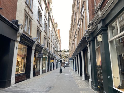 Cecil Court's Victorian shopfronts either side of a narrow paved lane, garlands strung overhead
