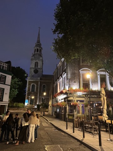 Clerkenwell Green at night, the lit front of the Crown Tavern on the right and the spire of St James's behind