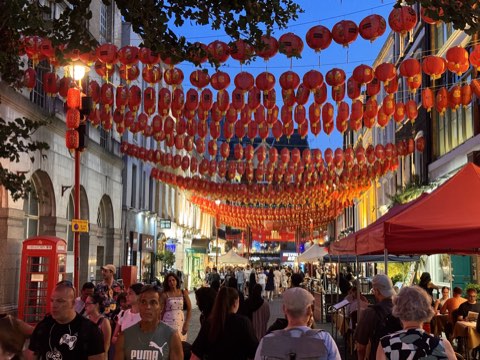 Gerrard Street in Chinatown at dusk, rows of red lanterns overhead and a red telephone box below