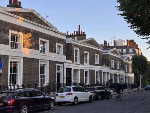 Paired brick houses on Lloyd Square, each pair under a single wide pediment, cars along the kerb