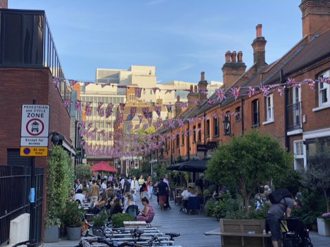 Pavilion Road under Union Jack bunting, tables outside the red-brick shop terrace