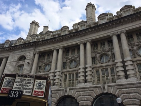 A vintage double-decker bus on display below the giant columns of the Quadrant, Regent Street's curved end