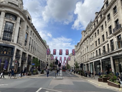 Union flags strung across Regent Street between the Portland stone frontages, the road curving away south