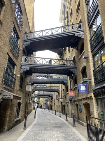 Shad Thames, iron gangways crossing overhead between tall brick warehouses above a cobbled street