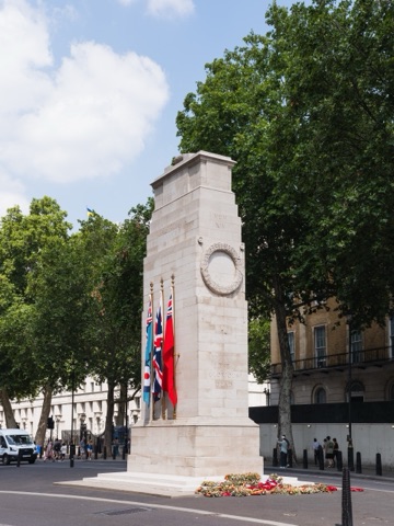 The Cenotaph on Whitehall, the United Kingdom's national war memorial, seen at three-quarters with its flags and the wreaths laid at its base. London, England. Panorama stitched from 2 source photographs