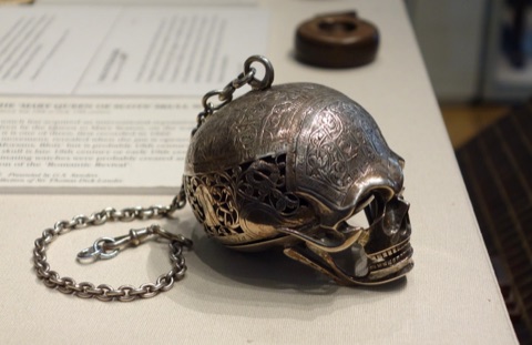 A silver watch made in the shape of a skull, on a chain, its hinged jaw open