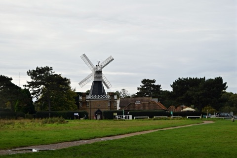 The weatherboarded windmill on Wimbledon Common, white sails against the sky
